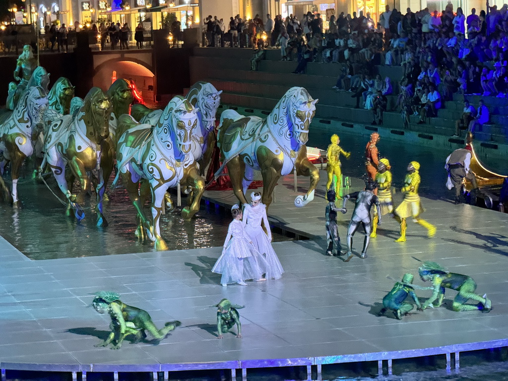 Boats, actors and horse statues in front of the Chateau at the Shopping Avenue area of the Land of Legends theme park, during the Musical Boat Parade, by night