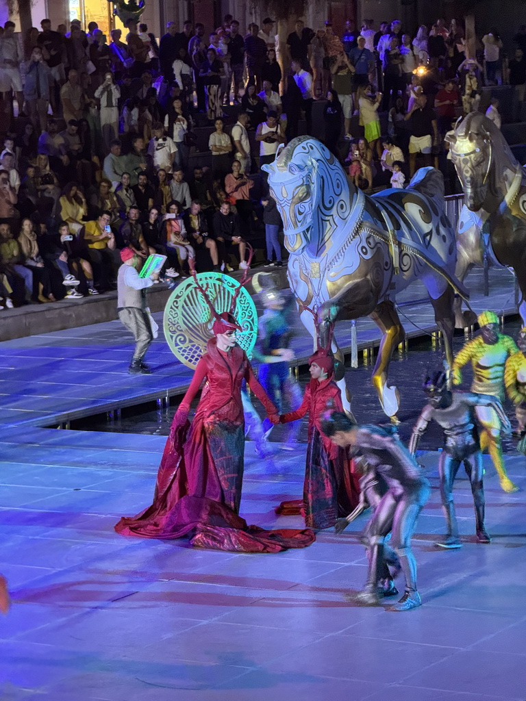 Actors and horse statues in front of the Chateau at the Shopping Avenue area of the Land of Legends theme park, during the Musical Boat Parade, by night