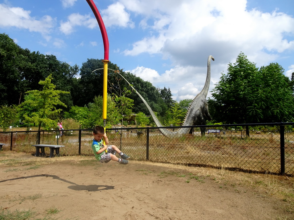 Max at the playground and a statue of a Diplodocus in the Garden of the Oertijdmuseum