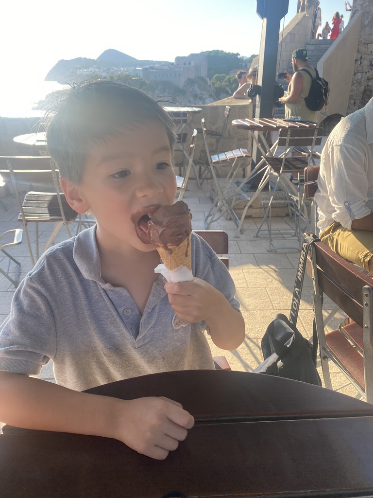 Max having an ice cream at the terrace of the Caffe on the Wall restaurant at the top of the Kula sv. Petra fortress, with a view on Fort Lovrijenac and the Velika Petka Hill