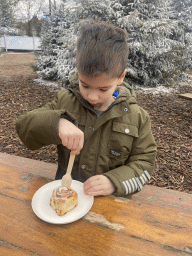 Max eating a cinnamon cake at the Warme Winter Weide square at the Reizenrijk kingdom, during the Winter Efteling