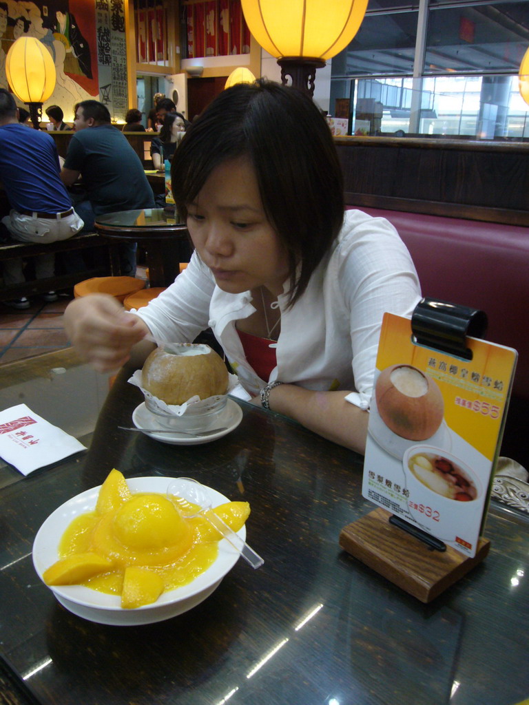 Miaomiao eating from a coconut in a restaurant at Hong Kong International Airport