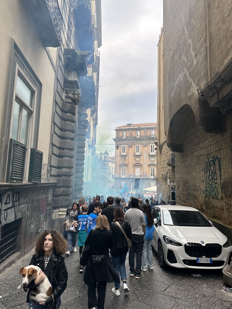 The Vico San Domenico Maggiore street with the northeast side of the Chiesa di San Domenico Maggiore church and SSC Napoli football fans at the Piazza San Domenico Maggiore square