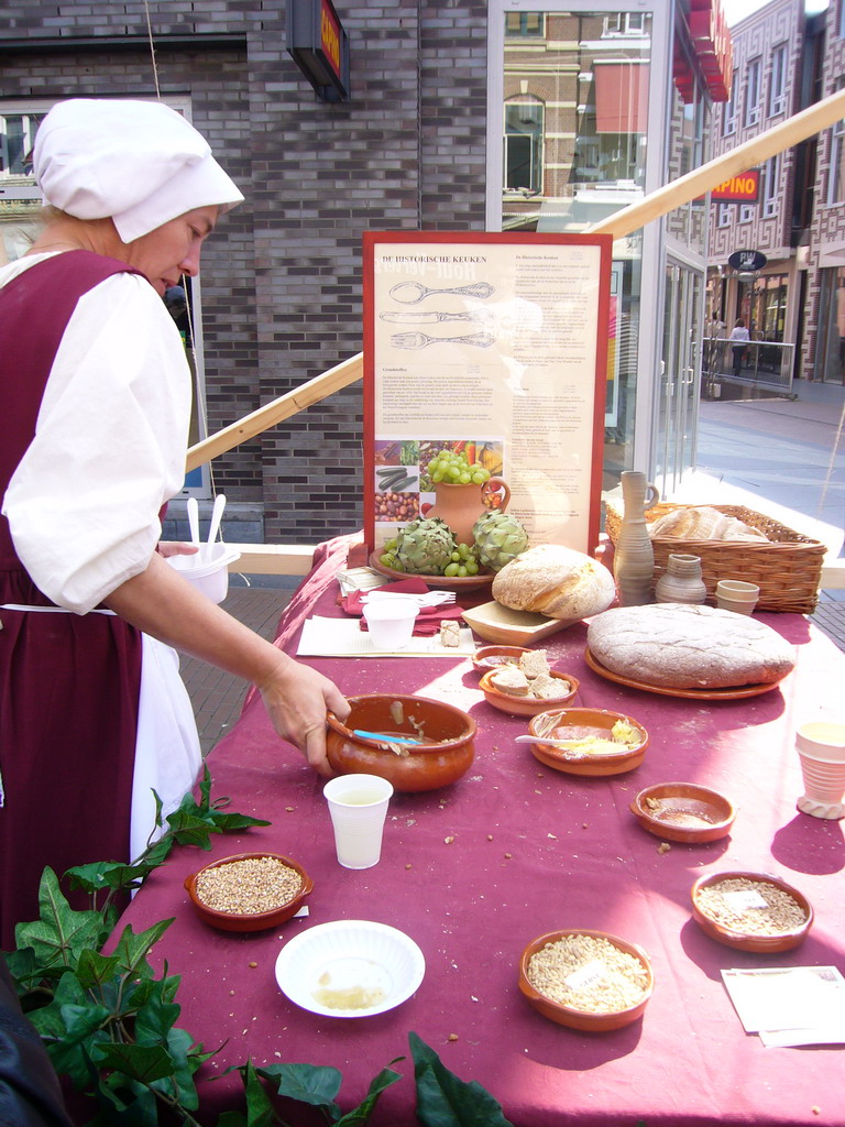 Person in medieval clothes selling bread at the Broerstraat street, during the Gebroeders van Limburg Festival