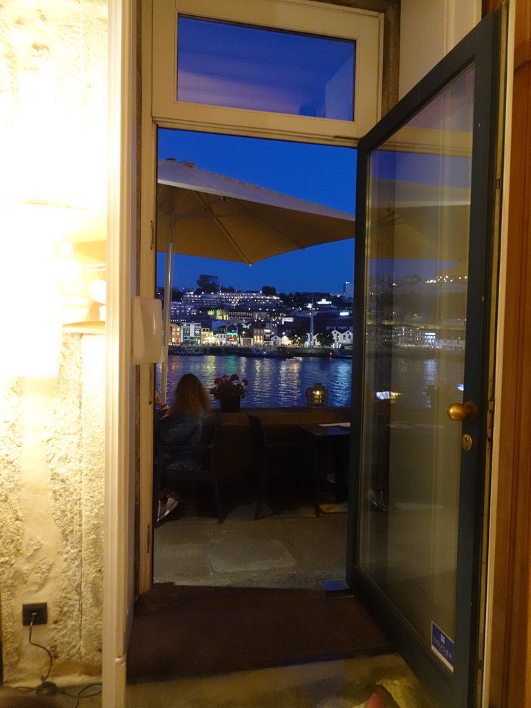 Boats on the Douro river and Vila Nova de Gaia with the Avenida de Diogo Leite street, viewed through the entrance to the Muro do Bacalhau restaurant, at sunset