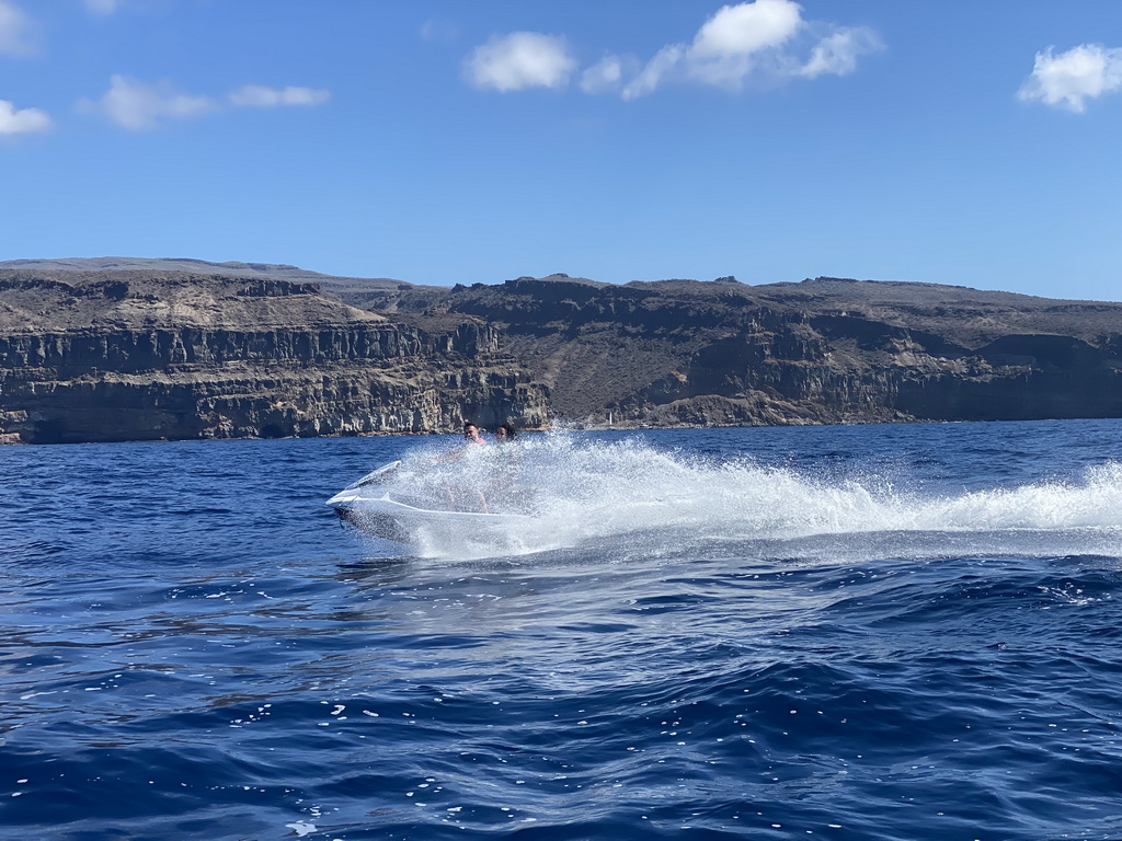 Jet ski and parasail in front of the coastline, viewed from a small boat from the jet ski to the Sagitarius Cat boat