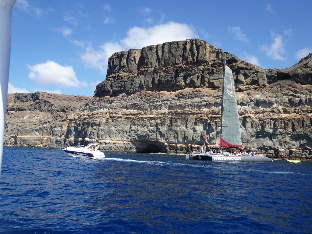 Boats in front of the coastline with a cave, viewed from the Sagitarius Cat boat