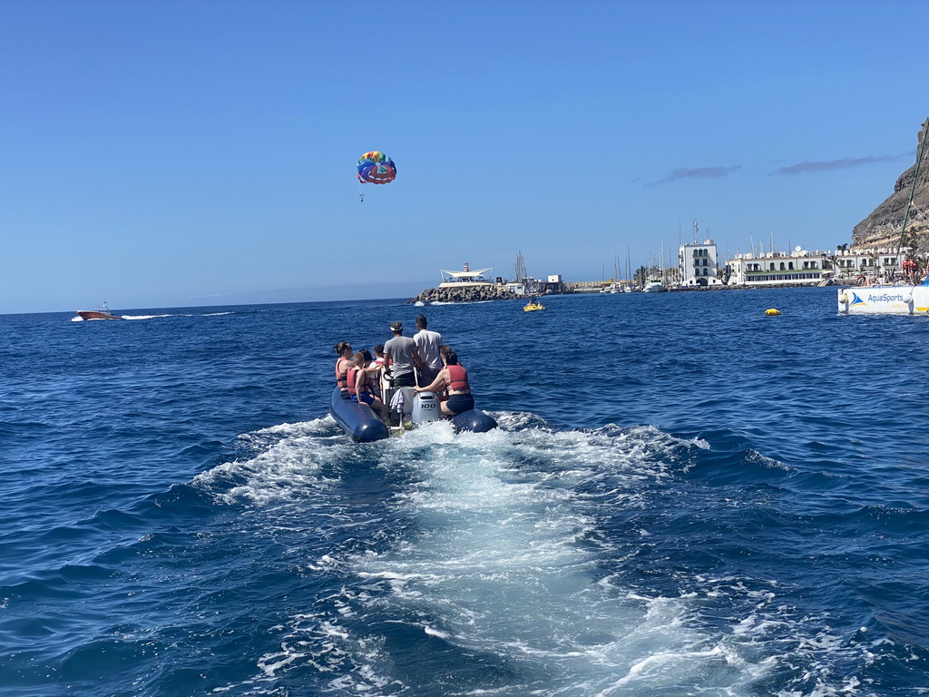 Small boat from the Sagitarius Cat boat to the parasail, in front of the town center with the pavilion of Beach Club Faro, the harbour and the Hotel THe Puerto de Mogán, viewed from the Sagitarius Cat boat