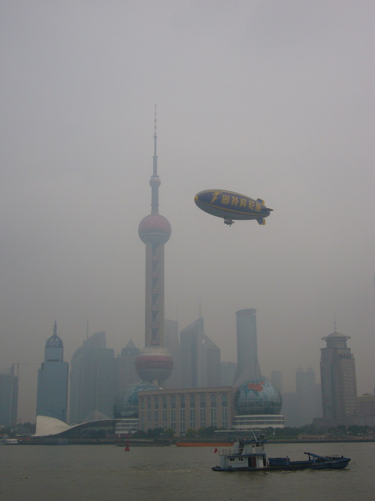 Boat in Huangpu river and the skyline of the Pudong district, with the Oriental Pearl Tower and a zappelin