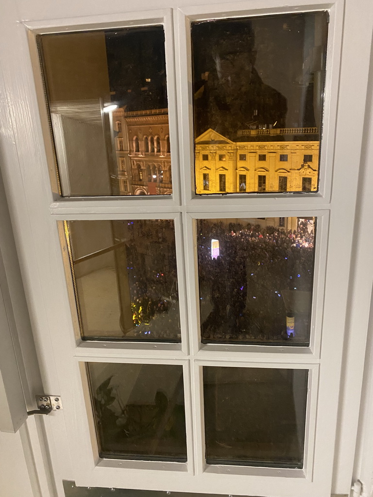 Window at the staircase from the third to the fourth floor of the Benediktushaus im Schottenstift hotel, with a view on the Silvesterpfad festivities at the Freyung square, by night