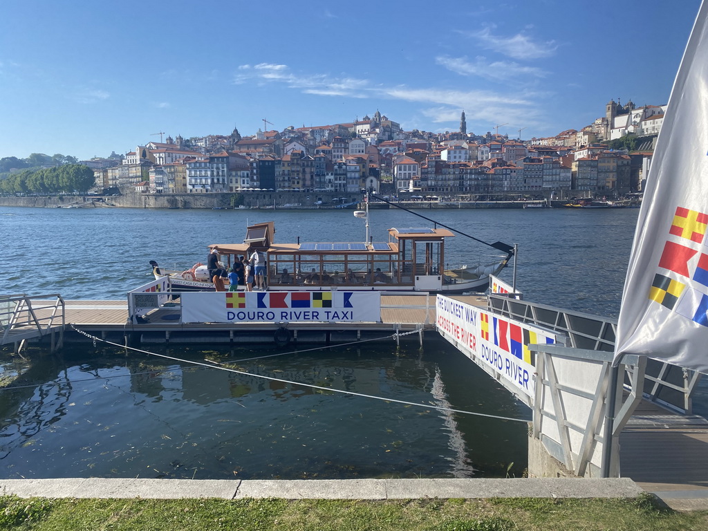 The ferry over the Douro river at the ferry dock at the Avenida de Diogo Leite street and Porto with the Cais da Estiva and Cais da Ribeira streets, the Igreja de Nossa Senhora da Vitória church, the Torre dos Clérigos tower and the Igreja dos Grilos church